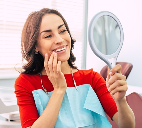 Woman in dental chair looking at smile