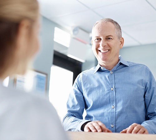 Man checking in at dental office reception desk