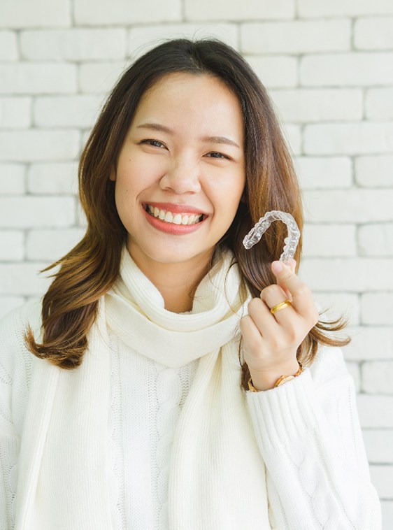 Woman smiling while holding ClearCorrect® aligners