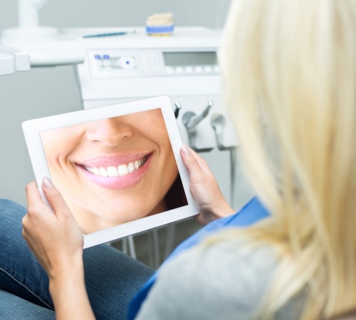 Woman looking at virtual smile design on tablet computer