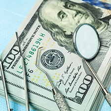 Dental instruments on stack of $100 bills