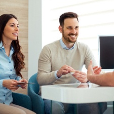 Man and woman talking with dentist at desk