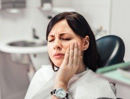 Woman in need of emergency dentistry holding jaw
