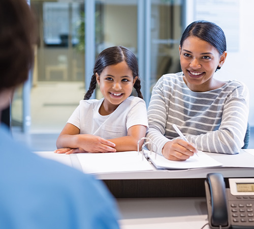 Mother and daughter checking in at dental office reception desk