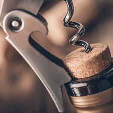 Closeup of wine bottle being opened using wine key