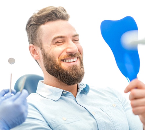 man with veneers in Houston smiles in mirror